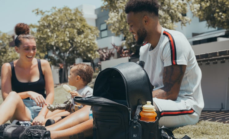 Young family in the park with ONE NINE baby bag